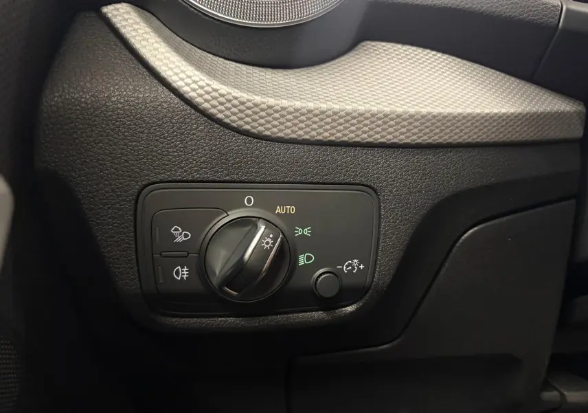 Gros plan sur le bouton de commande des phares dans l’habitacle noir de l’Audi Q2 35 TFSI S Line 2026.