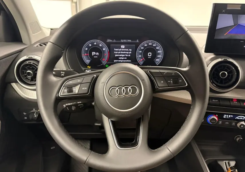 Vue centrée sur le volant multifonction de l'Audi Q2 35 TFSI S Line 2026 avec tableau de bord digital et aérateurs ronds.