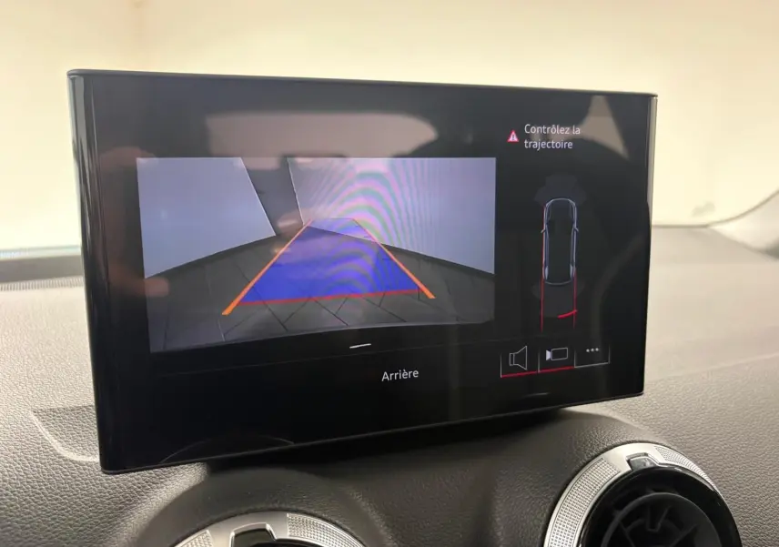 Écran intérieur montrant la caméra de recul avec guidage de trajectoire d’un Audi Q2 Noir Mythic, vue de face.