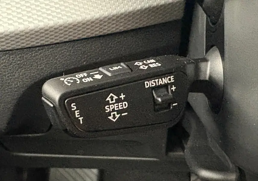 Gros plan sur la commande de régulateur de vitesse adaptatif noire dans l'habitacle de l'Audi Q2.