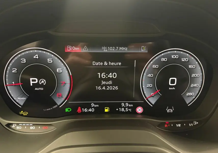Vue rapprochée du tableau de bord numérique de l'Audi Q2 35 TFSI 150 S Line affichant la date, l'heure et les compteurs.