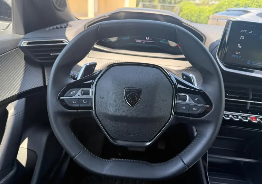 Vue intérieure centrée sur le volant noir du Peugeot 2008 Hybrid 136 e-DCS6 Style avec tableau de bord et écran tactile visibles.