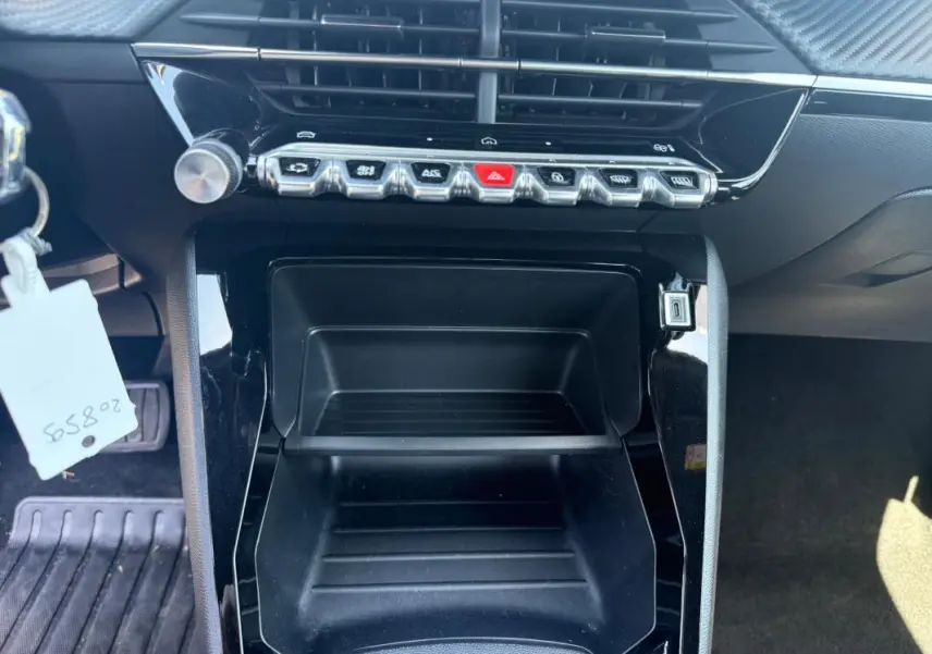 Vue rapprochée de la console centrale noire du Peugeot 2008 Hybrid 136 e-DCS6 Style 2025 avec boutons de commande et prise USB.