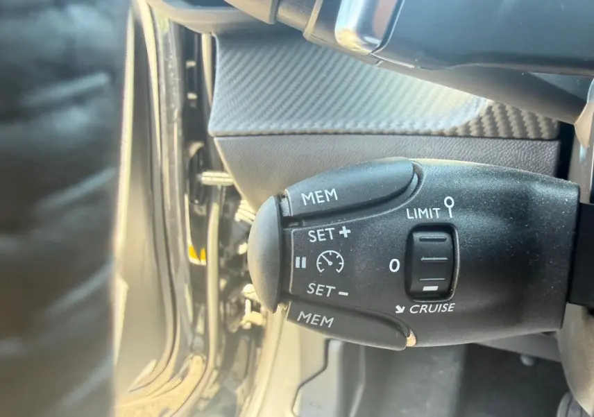 Gros plan sur la commande de régulateur de vitesse du Peugeot 2008 Hybrid 136 e-DCS6 Style noir, intérieur côté gauche.