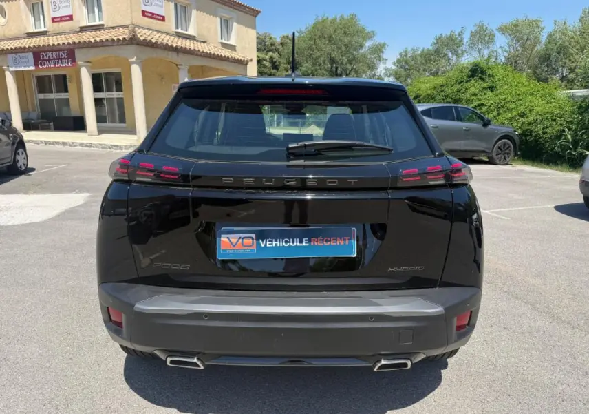 Vue arrière d'un Peugeot 2008 Hybrid noir 2025 avec feux LED caractéristiques et double sortie d'échappement.