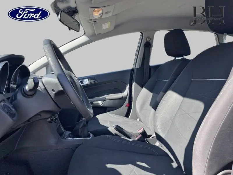 Vue intérieure côté conducteur de la Ford Fiesta noire 2015, montrant les sièges avant et le volant à gauche.