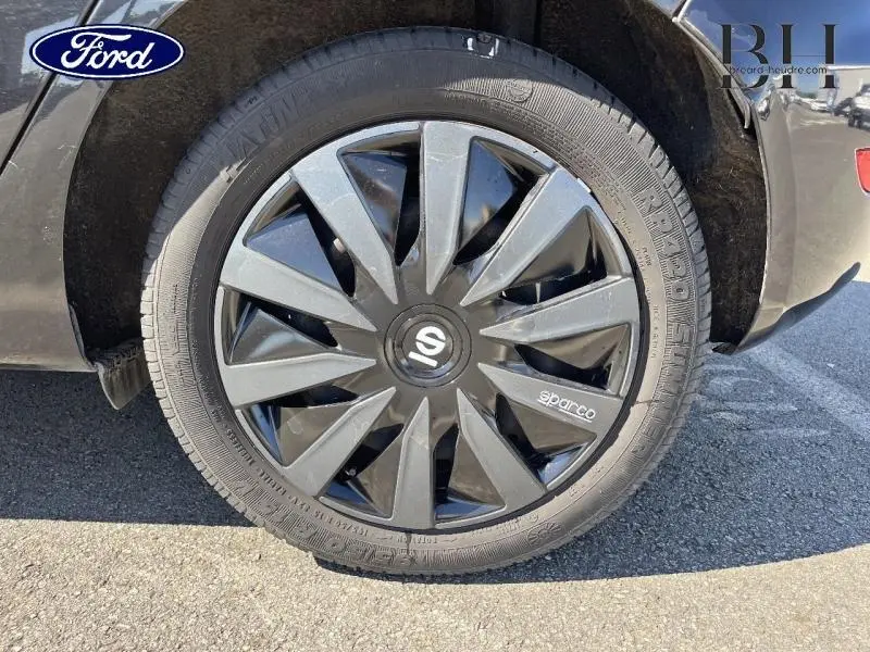 Gros plan sur la roue arrière droite noire d'une Ford Fiesta 2015 avec jante Sparco au design moderne.