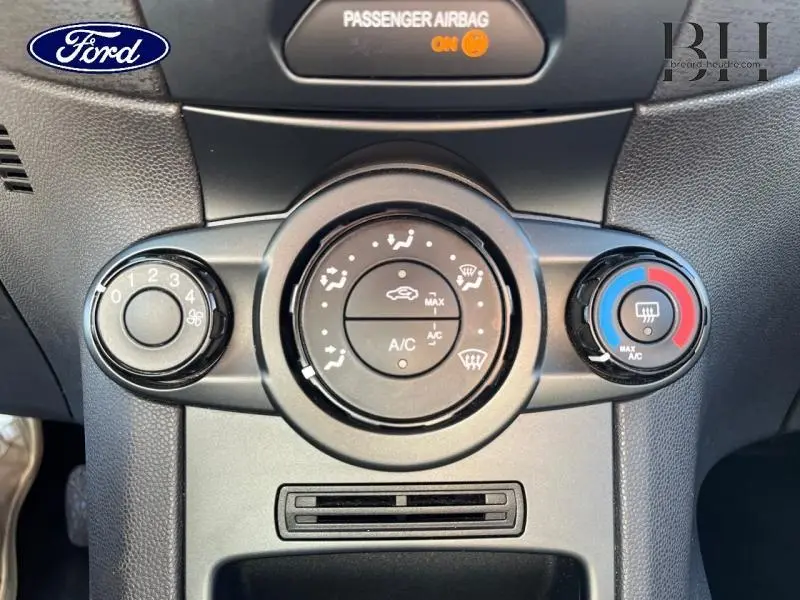 Vue rapprochée du tableau de bord de la Ford Fiesta 2015 noir, montrant les commandes de climatisation circulaires.