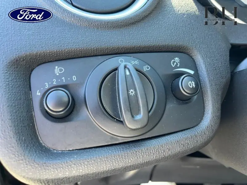 Gros plan sur le panneau de commande des phares intérieur d'une Ford Fiesta noire 2015, avec réglages de lumière visibles.