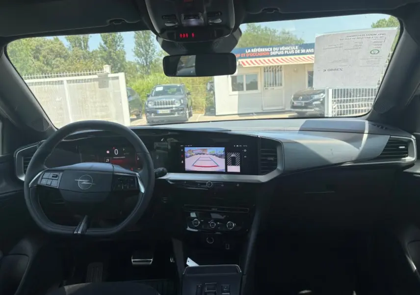 Vue intérieure avant de l'Opel Mokka électrique 2025, tableau de bord avec écran tactile et volant multifonction noir.