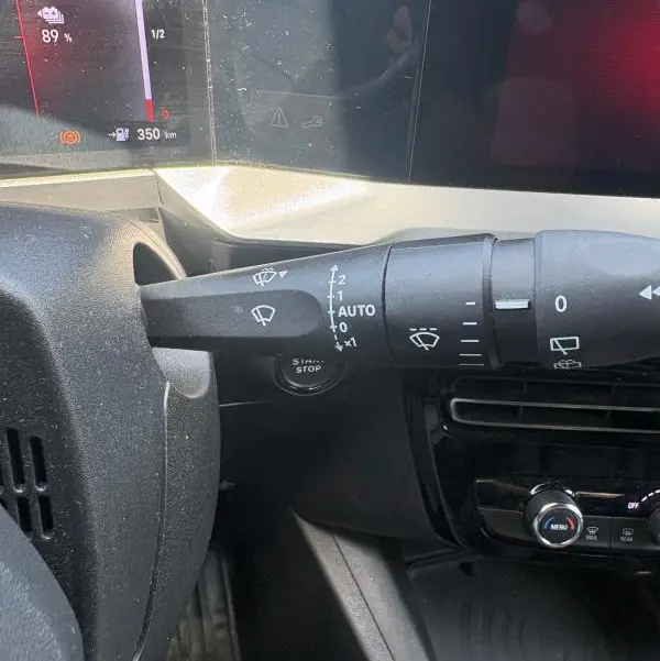 Gros plan sur la commande des essuie-glaces à gauche du volant dans l'habitacle d'un Opel Mokka électrique gris 2025.