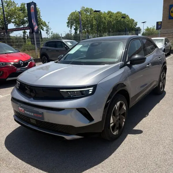 Opel Mokka électrique gris en 3/4 avant droit, avec jantes alliage 17 pouces et vitres surteintées.