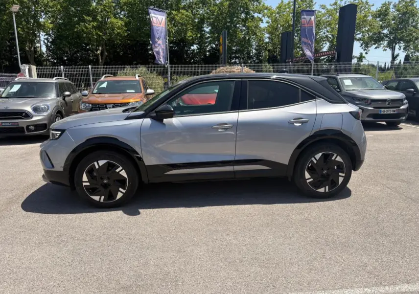Opel Mokka électrique gris vue de profil côté gauche, avec toit noir et jantes alliage 17 pouces, vitres surteintées.