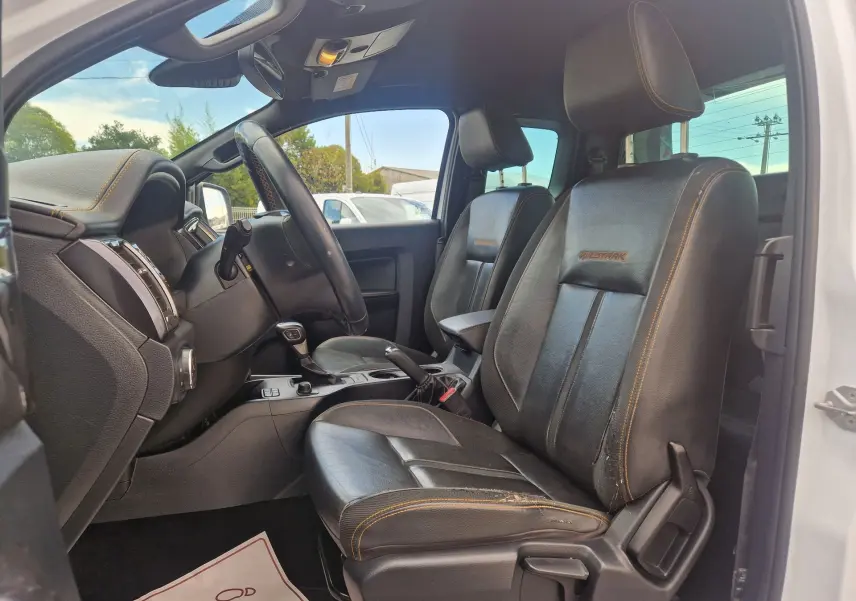 Intérieur côté conducteur du Ford Ranger Wildtrak 2020, sièges cuir noirs avec surpiqûres orange et logo Wildtrak brodé.