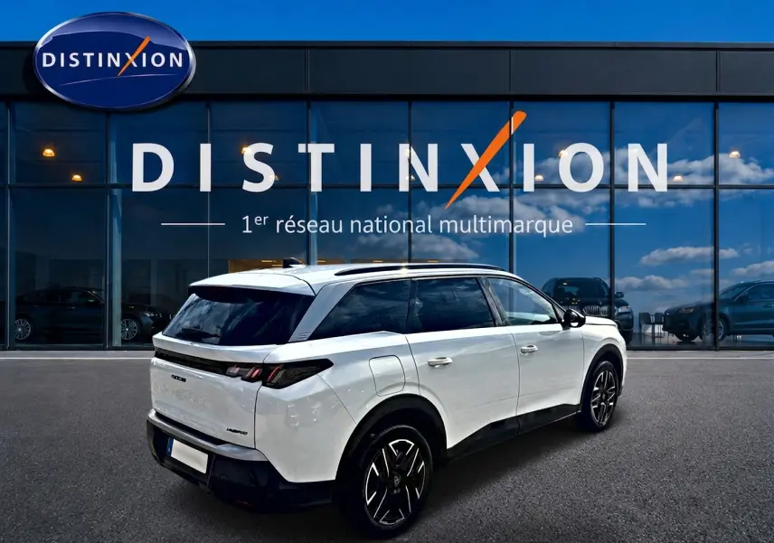 Peugeot 5008 Hybrid 145 allure blanc en 3/4 arrière droit, avec vitres arrière surteintées et jantes alu noires.