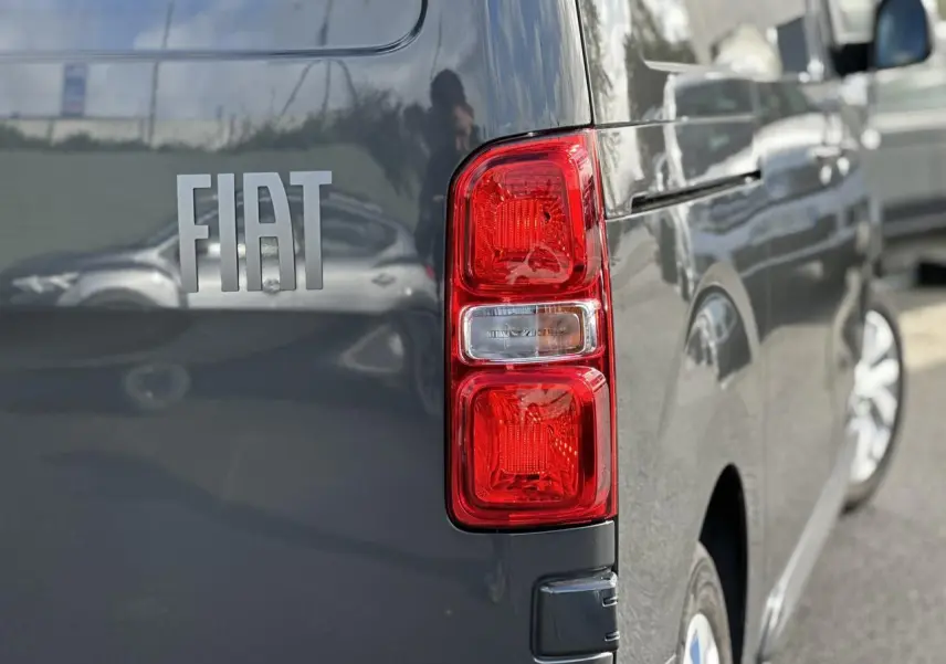 Gros plan sur le feu arrière droit d’un FIAT Scudo Fourgon gris Platinium avec reflet de la carrosserie.