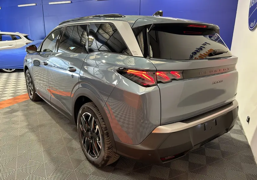 Vue 3/4 arrière droite du Peugeot 5008 bleu Ingaro avec feux arrière LED et toit ouvrant panoramique visible.