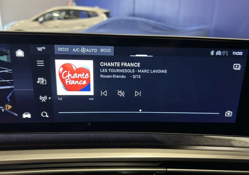 Écran tactile intérieur du Peugeot 5008 III Hybrid 145 GT affichant la radio Chante France, avec tableau de bord en arrière-plan.