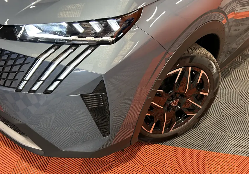 Gros plan sur l’avant droit bleu Ingaro du Peugeot 5008 III Hybrid 145 avec phares LED et jante alliage noire.