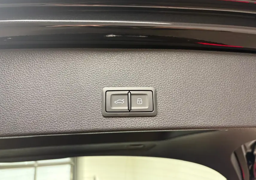 Boutons de commande du hayon électrique sur la partie intérieure du coffre d’un Audi Q2 Noir Mythic, vue rapprochée.