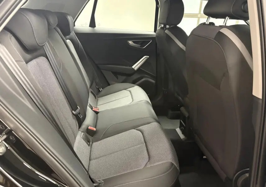 Vue intérieure du côté gauche des sièges arrière de l'Audi Q2 35 TFSI S Line 2026 en tissu gris et noir.