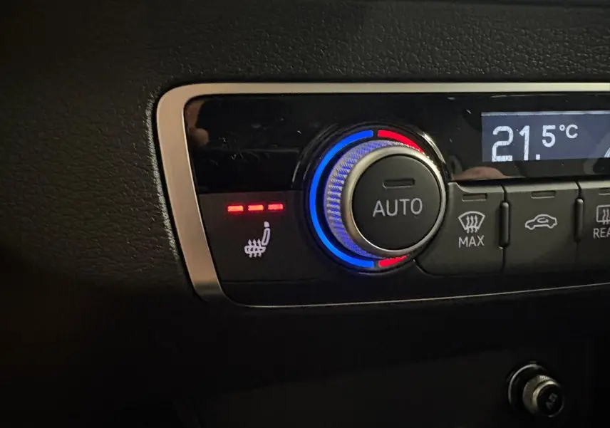 Gros plan sur le bouton de réglage de la climatisation avec fonction siège chauffant activée dans l’Audi Q2 35 TFSI S Line.
