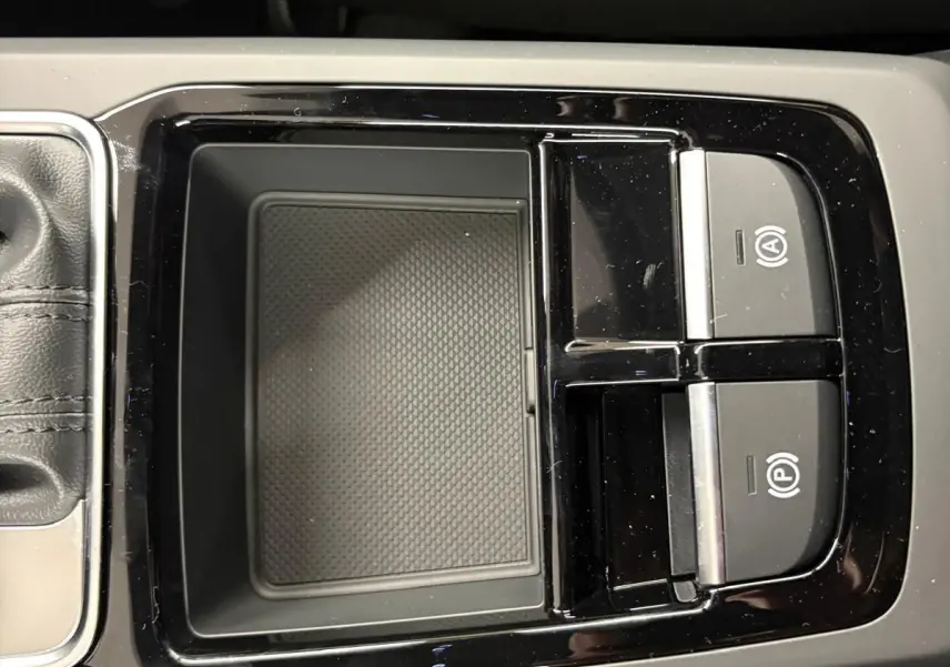 Gros plan sur la console centrale noire brillante de l'Audi Q2 35 TFSI S Line avec commandes de frein à main électrique.