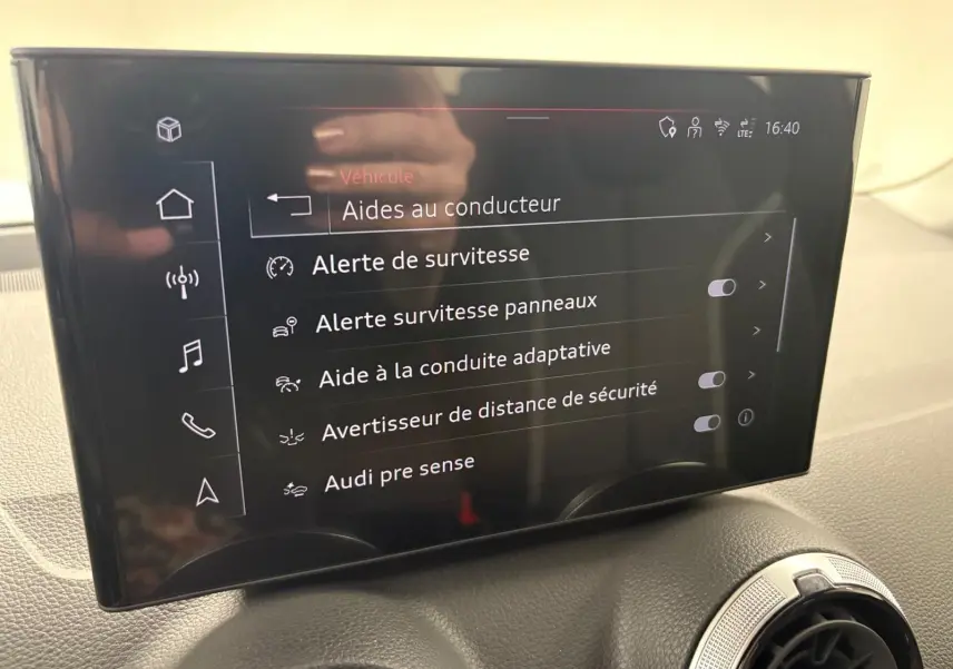 Écran tactile central de l'Audi Q2 35 TFSI S Line 2026 affichant les aides à la conduite, intérieur noir.