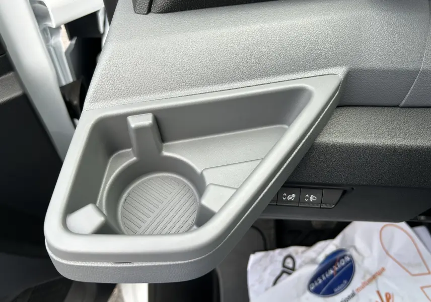 Gros plan sur le porte-gobelet gris intégré côté conducteur du tableau de bord du Renault Master blanc 2025.