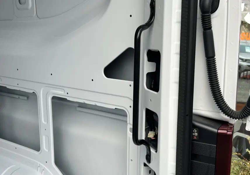 Vue rapprochée de l’intérieur de la porte arrière blanche du Renault Master IV L2H2, avec poignée noire et partie du feu arrière visible.