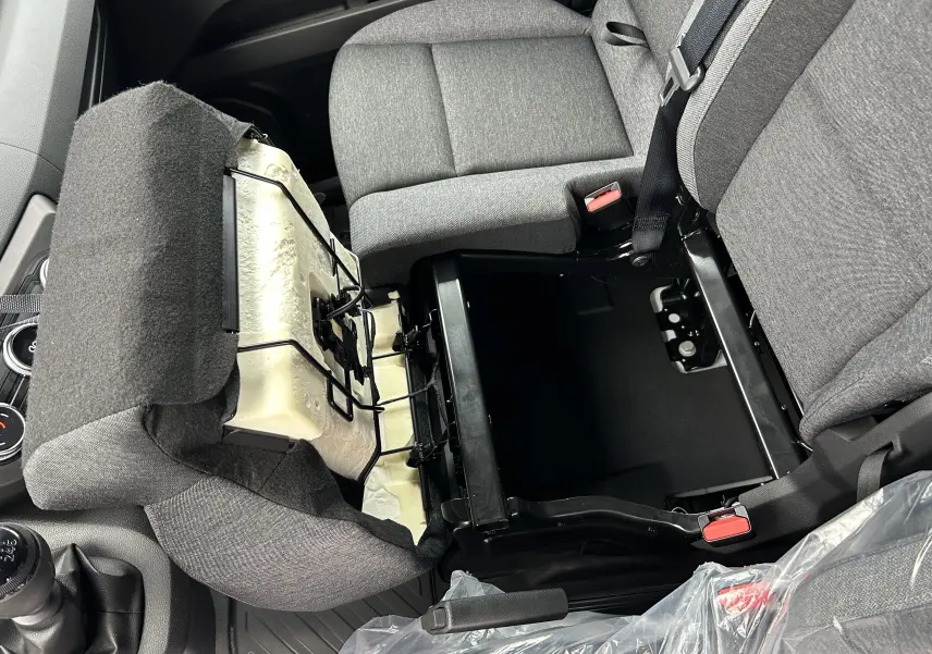 Vue intérieure du siège conducteur relevé du Renault Master IV L2H2 blanc, montrant le rangement sous le siège et la sellerie grise.