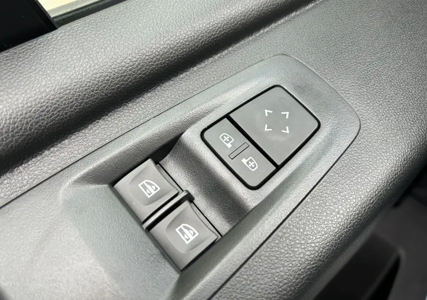 Gros plan sur les commandes de réglage des rétroviseurs et des vitres électriques côté conducteur du Renault Master blanc 2025.