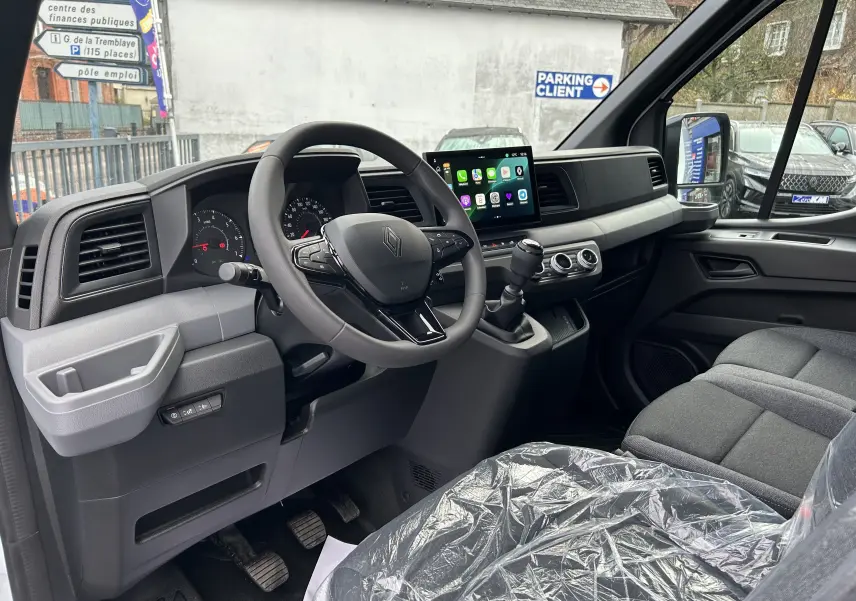 Vue intérieure côté conducteur du Renault Master blanc 2025, montrant le tableau de bord moderne avec écran tactile et volant multifonction.