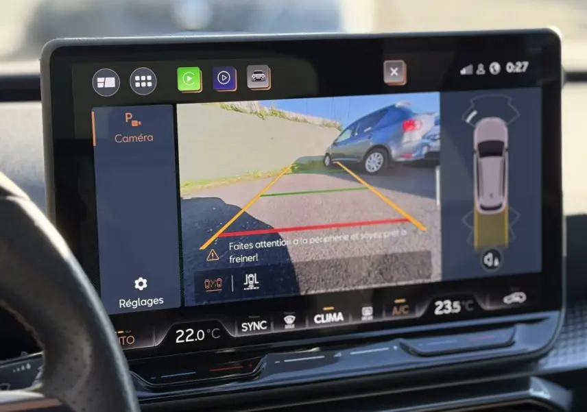 Écran tactile du système d'info-divertissement montrant la caméra de recul d'une CUPRA Leon ST noire en stationnement.