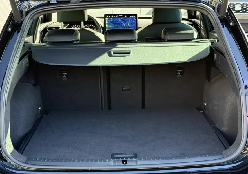 Coffre ouvert d'une CUPRA LEON ST noir Midnight, vue arrière montrant l'habitacle et l'écran tactile du tableau de bord.