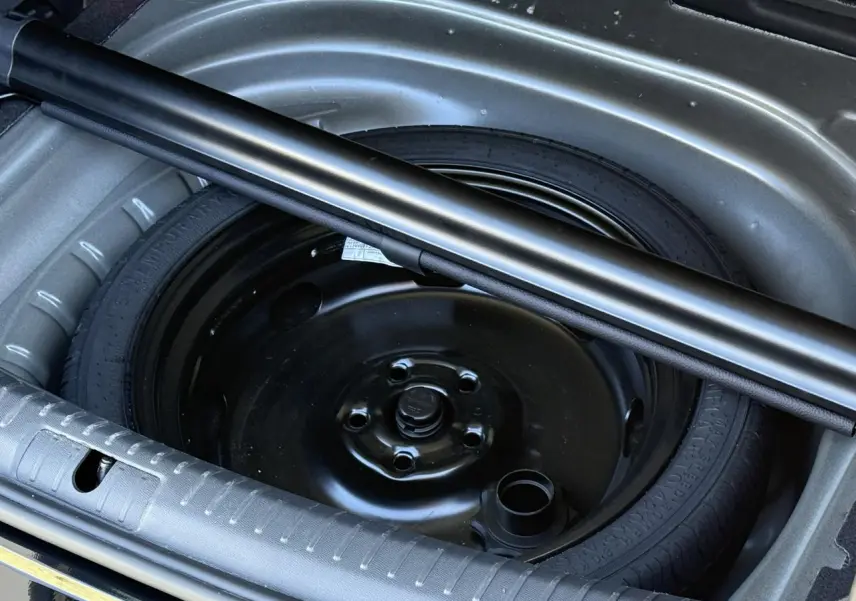 Gros plan sur la roue de secours noire dans le coffre ouvert d'une CUPRA LEON ST 2025 Noir Midnight.