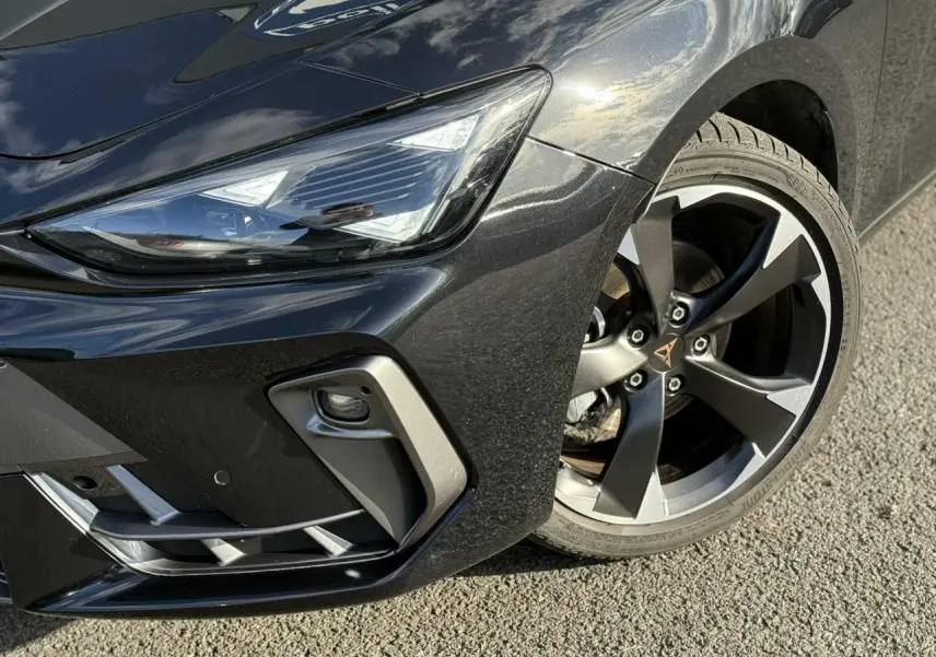 Gros plan sur l'avant droit noir Midnight de la CUPRA LEON ST 2025, mettant en valeur le projecteur Tri-LED et la jante alliage 18 pouces.