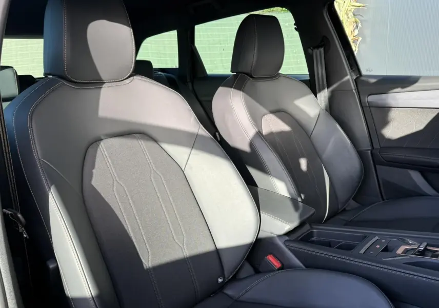 Vue intérieure côté avant droit des sièges en cuir noir et tissu du CUPRA LEON ST 2025 avec accoudoir central.