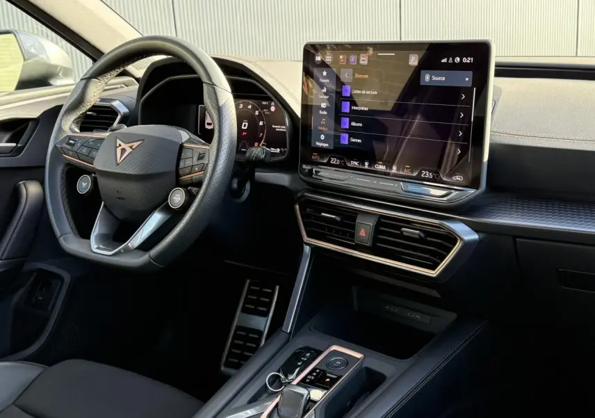 Vue intérieure côté conducteur du CUPRA LEON ST 2025, volant cuir noir et écran tactile HD central lumineux.