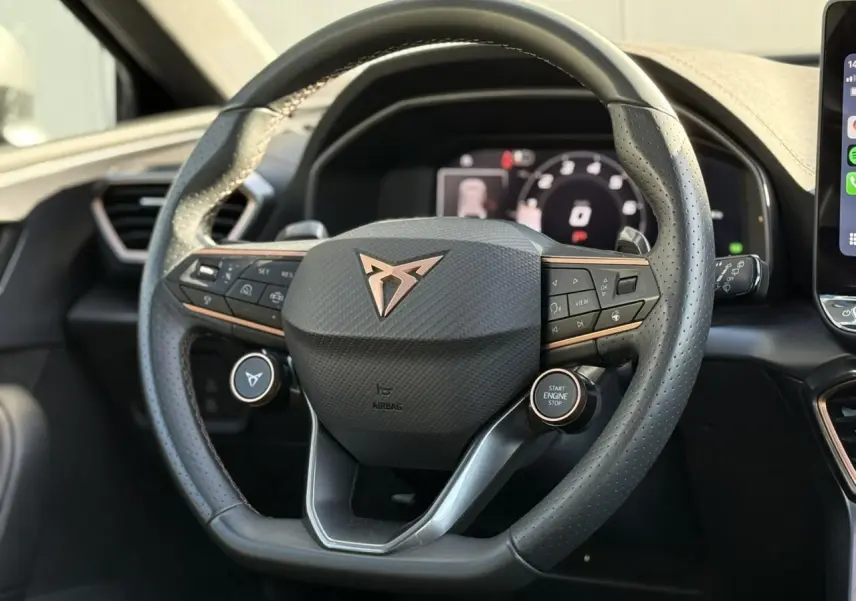Volant CUPRA noir avec logo cuivré et commandes intégrées, vue rapprochée du poste de conduite du Leon ST 2025.