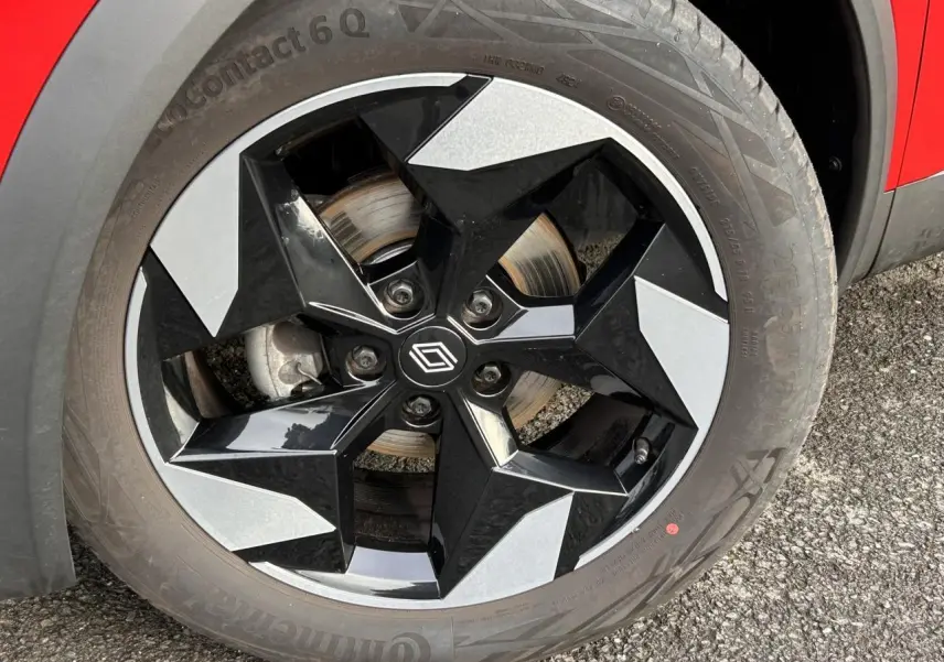 Gros plan sur la jante alu 18 pouces diamantée noire du Renault Captur Rouge Flamme avec partie de la carrosserie visible.