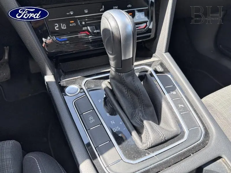 Gros plan sur le levier de vitesses automatique en cuir noir de la Volkswagen Passat SW gris manganèse, avec commandes autour.
