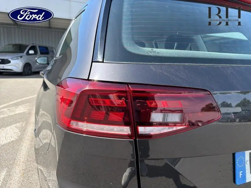 Gros plan sur le feu arrière droit d’une Volkswagen Passat SW gris manganèse métallisé, avec lunette arrière teintée.