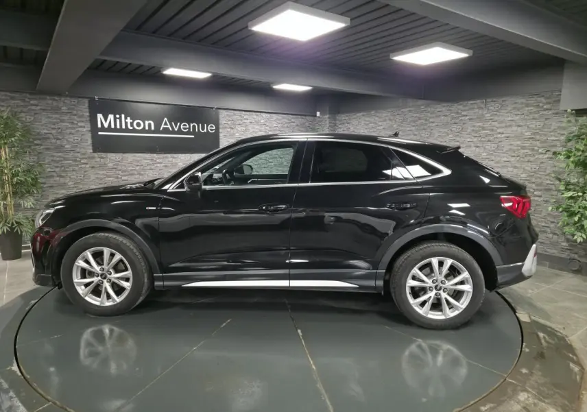 Audi Q3 Sportback noir vue de profil côté gauche, avec jantes 5 branches et vitres arrière surteintées.