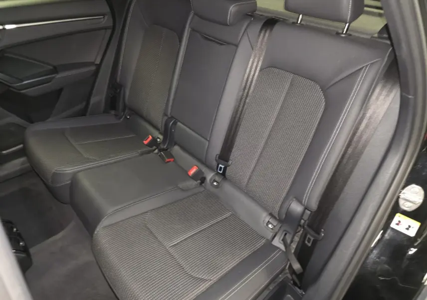 Vue côté droit de la banquette arrière noire de l'Audi Q3 Sportback 2023 avec ceintures et appuie-têtes visibles.