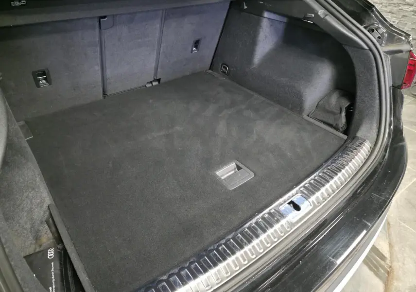 Coffre ouvert de l'Audi Q3 Sportback noir, vue en plongée montrant la surface et la protection en acier inoxydable du seuil.