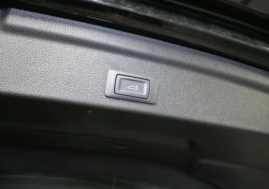 Bouton d'ouverture électrique du hayon sur la partie intérieure noire du coffre d'un Audi Q3 Sportback noir.