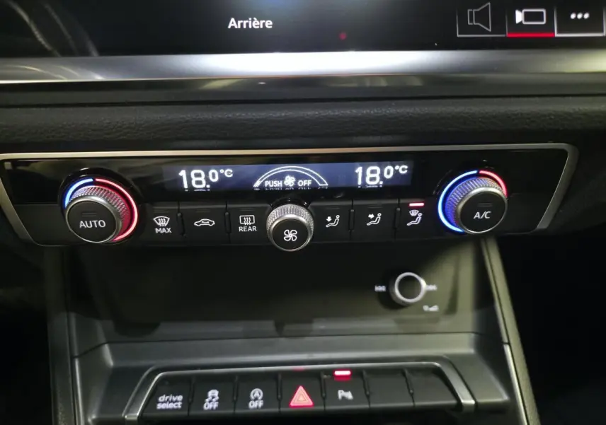 Vue rapprochée de la console centrale de l'Audi Q3 Sportback noire, affichant la climatisation automatique et les commandes.