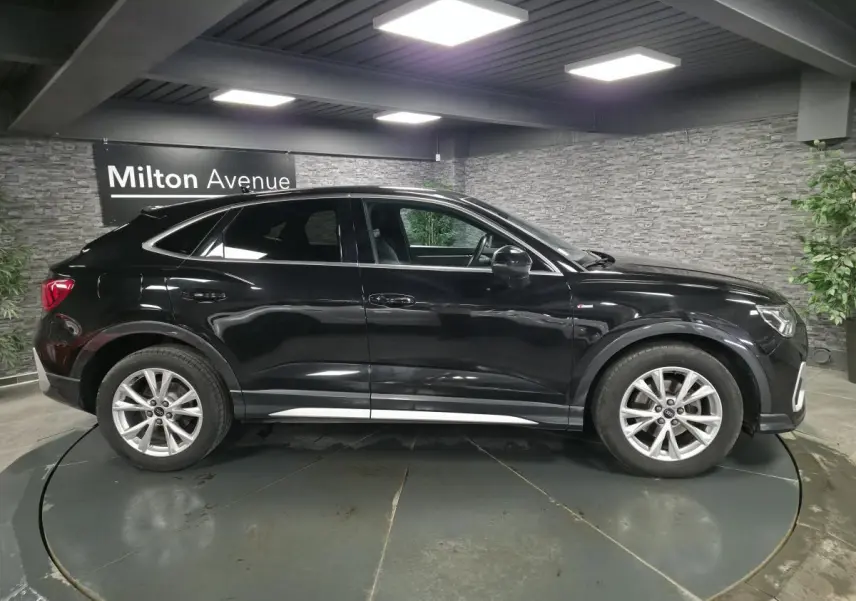 Audi Q3 Sportback noir vue de profil côté gauche, vitres arrière surteintées et jantes 18 pouces en aluminium.