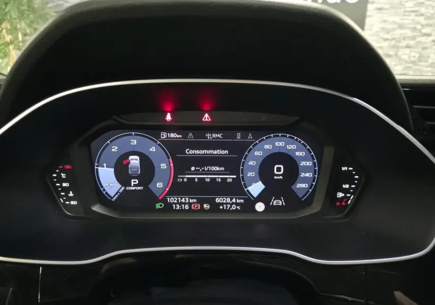 Vue rapprochée du combiné d'instruments numérique de l'Audi Q3 Sportback noir, affichant la consommation et la vitesse à 0 km/h.
